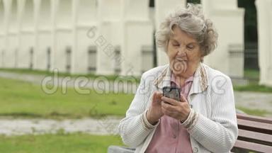 成熟的老妇人在户外手持<strong>银色</strong>智能<strong>手机</strong>